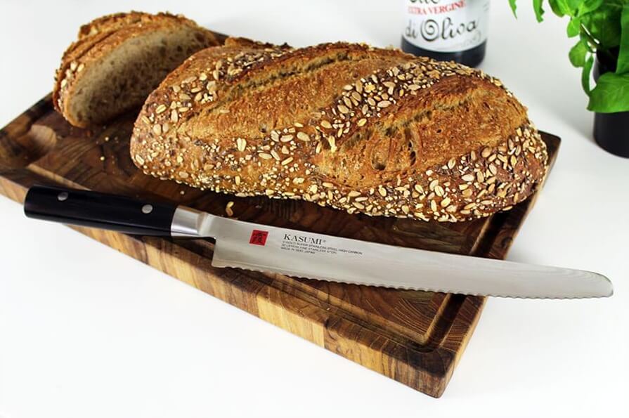 Japansk Brødkniv fra Kasumi på skærebræt med forskellige brød