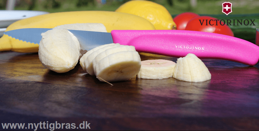 Victorinox Urtekniv 8 cm med bølgeskær i pink farve snitter i banan